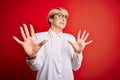 Young blonde business woman with short hair wearing glasses over red background afraid and terrified with fear expression stop Royalty Free Stock Photo