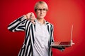 Young blonde business woman with short hair wearing glasses working using computer laptop with angry face, negative sign showing Royalty Free Stock Photo