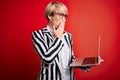 Young blonde business woman with short hair wearing glasses working using computer laptop cover mouth with hand shocked with shame Royalty Free Stock Photo