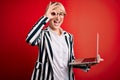 Young blonde business woman with short hair wearing glasses working using computer laptop with happy face smiling doing ok sign Royalty Free Stock Photo