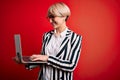 Young blonde business woman with short hair wearing glasses working using computer laptop with a happy face standing and smiling Royalty Free Stock Photo