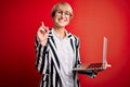 Young blonde business woman with short hair wearing glasses working using computer laptop surprised with an idea or question Royalty Free Stock Photo