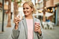 Young blonde businesswoman having breakfast at the city