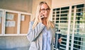 Young blonde businesswoman with serious expression talking on the smartphone and holding bottle of water at the city Royalty Free Stock Photo