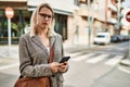 Young blonde businesswoman with serious expression using smartphone at the city Royalty Free Stock Photo