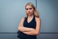 Young blonde businesswoman standing by modern business center with hands crossed. Confident, powerful, successful women