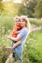 Young blonde Caucasian mother and boy toddler son hugging embracing in park outdoor on summer day. Mom and child love and Royalty Free Stock Photo