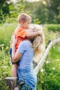 Young blonde Caucasian mother and boy toddler son hugging kissing in park outdoor on summer day. Royalty Free Stock Photo