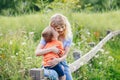 Young blonde Caucasian mother and boy toddler son hugging kissing in park outdoor on summer day. Royalty Free Stock Photo