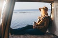 Young blonde Caucasian woman relaxing in her campervan at sunset