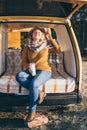 Young blonde Caucasian woman relaxing in her campervan at sunset