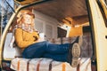 Young blonde Caucasian woman relaxing in her campervan at sunset