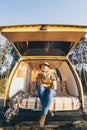 Young blonde Caucasian woman relaxing in her campervan at sunset