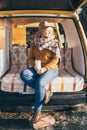 Young blonde Caucasian woman relaxing in her campervan at sunset