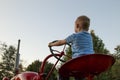 Young Blonde child pretending to drive a red tractor