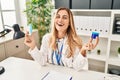 Young blonde doctor woman holding medicine products to breath better smiling and laughing hard out loud because funny crazy joke Royalty Free Stock Photo