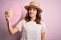 Young blonde fashion girl using wooden spanish hand fan on a hot summer day with a happy face standing and smiling with a Royalty Free Stock Photo