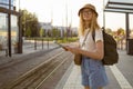 Young blonde female tourist traveler looking for the right direction on a trip map at the bus stop on a city street Royalty Free Stock Photo