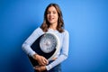 Young blonde fitness girl holding scale dieting for heatlhy weight over blue background with a happy face standing and smiling Royalty Free Stock Photo