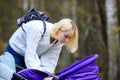 A young blonde with freckles short haircut white sweater bent over a baby stroller