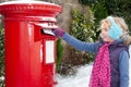 Young blonde girl in blue ear muffs posting her letter to Santa Royalty Free Stock Photo