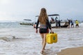 Young blonde girl in diving suit carries a medical case with first aid to the boat, which is pushed out by a group of Royalty Free Stock Photo