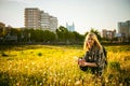 Young blonde girl in dress with shoulder bag, walking on dandelion field Royalty Free Stock Photo