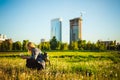 Young blonde girl in dress with shoulder bag, walking on dandelion field Royalty Free Stock Photo