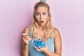 Young blonde girl eating measure meter doing diet for weight loss afraid and shocked with surprise and amazed expression, fear and Royalty Free Stock Photo