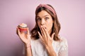 Young blonde girl eating a sweet chocolate cupcake over pink isolated background cover mouth with hand shocked with shame for Royalty Free Stock Photo