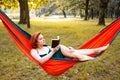 Young blonde girl in hammock reading book. Pretty woman leisure lifestyle at nature ountdoor. Female relax in forest. Royalty Free Stock Photo