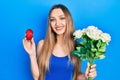 Young blonde girl holding bouquet of flowers and engagement ring smiling with a happy and cool smile on face Royalty Free Stock Photo