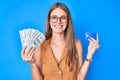 Young blonde girl holding credit car and dollars smiling with a happy and cool smile on face Royalty Free Stock Photo