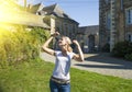 Young blonde girl holding grape in front of old French buildings in Provence