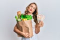 Young blonde girl holding paper bag with groceries and pounds looking at the camera blowing a kiss being lovely and sexy
