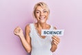 Young blonde girl holding paper with science message screaming proud, celebrating victory and success very excited with raised arm