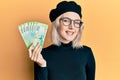 Young blonde girl holding russian 200 ruble banknotes looking positive and happy standing and smiling with a confident smile