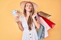 Young blonde girl holding shopping bags and canadian dollars looking at the camera blowing a kiss being lovely and sexy Royalty Free Stock Photo