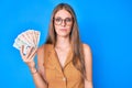 Young blonde girl holding united kingdom pounds relaxed with serious expression on face