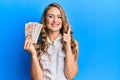 Young blonde girl holding united kingdom pounds smiling with an idea or question pointing finger with happy face, number one