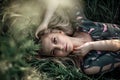 Young blonde girl with long hair lying in the grass.