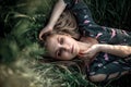 Young blonde girl with long hair lying in the grass.