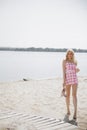 Young blonde girl look like a Barbie doll in pink mini dress walking barefoot on beach Royalty Free Stock Photo