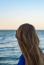 Young blonde girl looking sea and blue skies back view Royalty Free Stock Photo