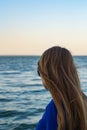 Young blonde girl looking sea and blue skies back view Royalty Free Stock Photo