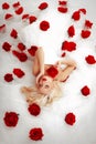 Blonde girl lying in a white dress with red roses Royalty Free Stock Photo