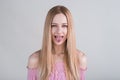 Young blonde girl makes funny grimaces in the studio on a white background.