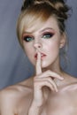 Young blonde girl over gray background asking to be quiet with finger on lips. Silence and secret concept Royalty Free Stock Photo