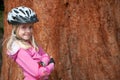 A young blonde girl poses in a cycle helmet and elbow pads