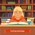 Young blonde girl reading book in a library